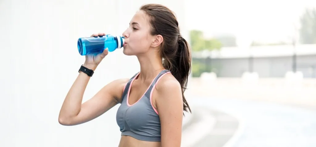 Active woman drinking water