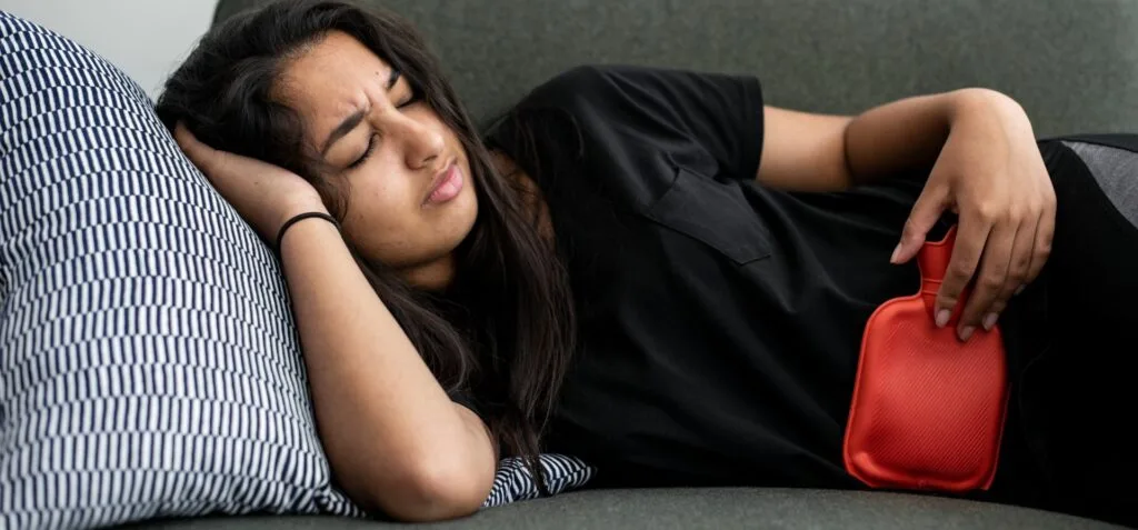 Young girl with using a hot compress on her stomach